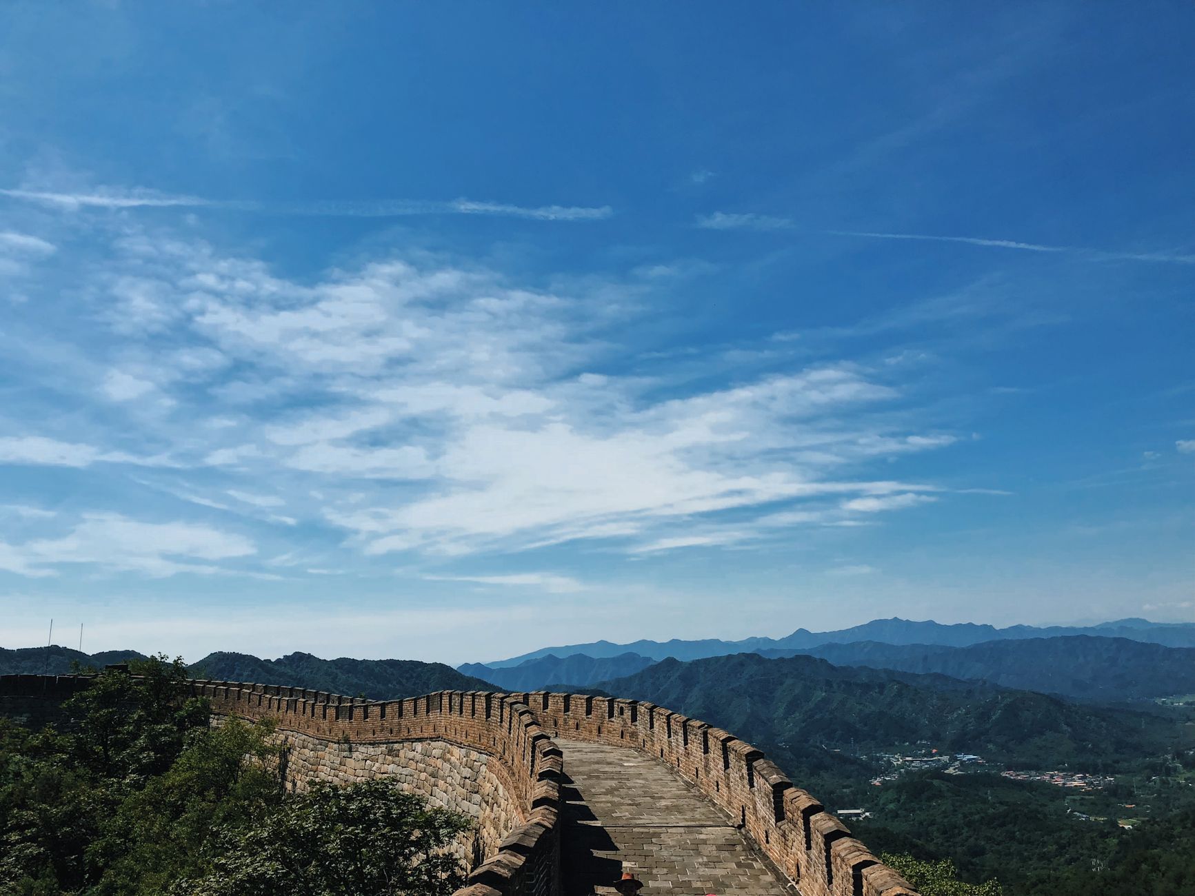 The Great Wall of China winding over forested mountains