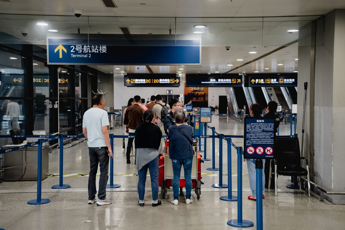 Viajeros haciendo cola en una terminal del aeropuerto de Shanghái con señalización bilingüe de llegadas