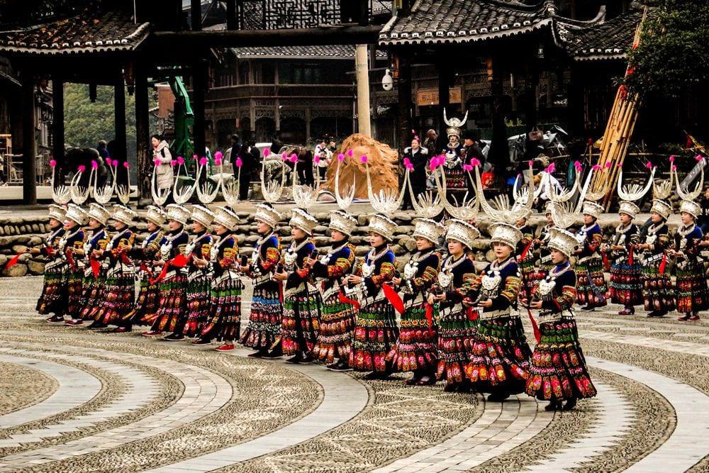 Intérpretes con trajes típicos en la Aldea de las Nacionalidades de Yunnan