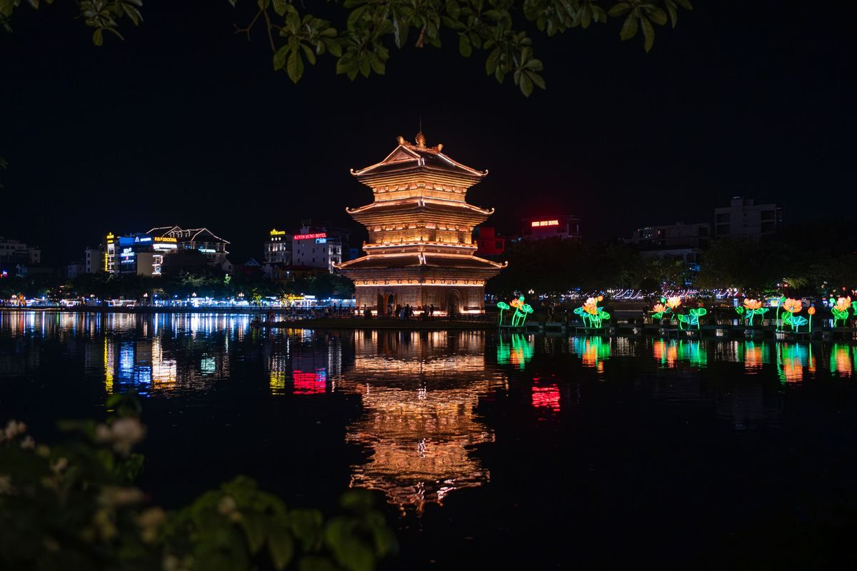 Un pabellón iluminado y faroles de loto reflejados en los lagos durante el crucero nocturno