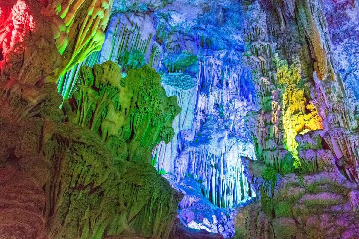 Estalactitas iluminadas de colores dentro de la Gruta de la Flauta de Caña