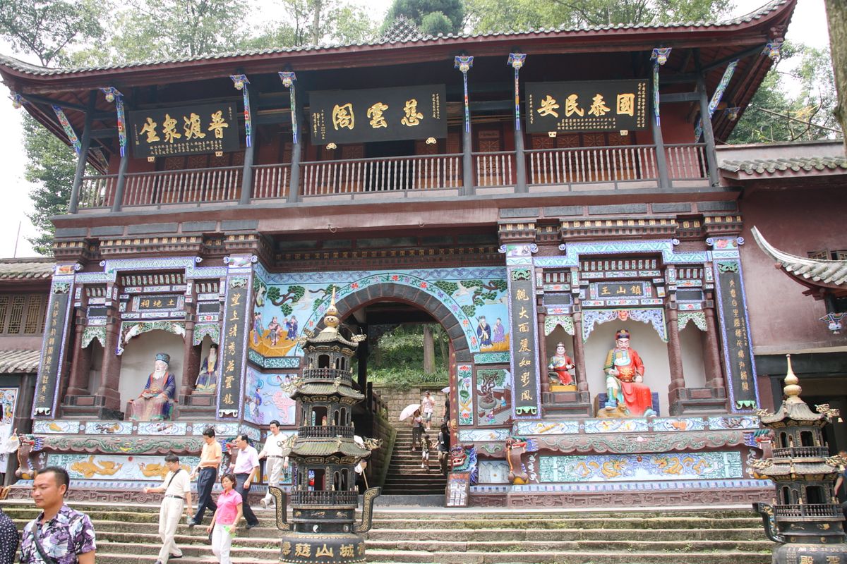 Sendero forestal brumoso y estructuras tradicionales en el Monte Qingcheng