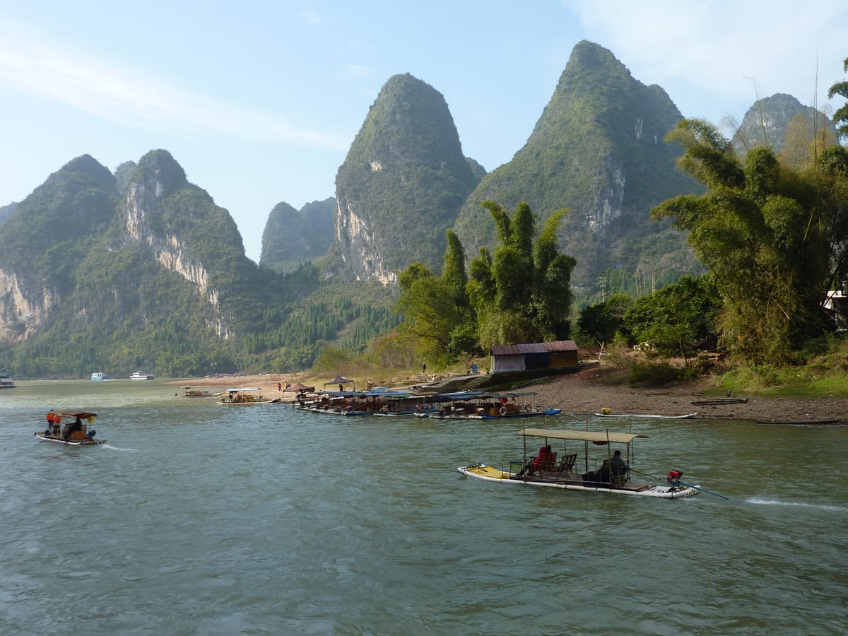 Bamboo rafts and a cruise boat on the Li River amid karst peaks near Yangshuo