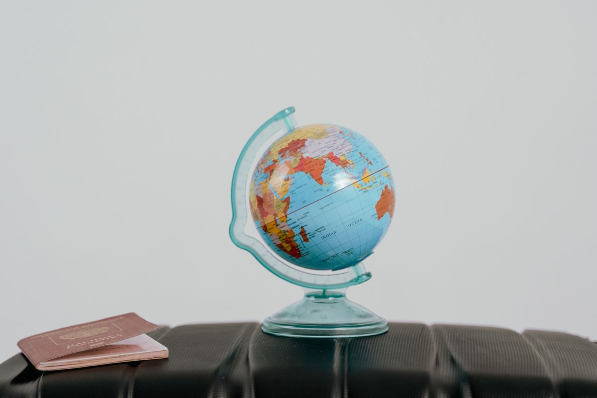 Un pequeño globo terráqueo y un pasaporte sobre una maleta, símbolo del viaje internacional