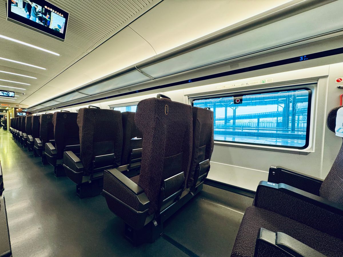 Interior de un moderno tren de alta velocidad chino con filas de asientos reclinables junto a una gran ventanilla