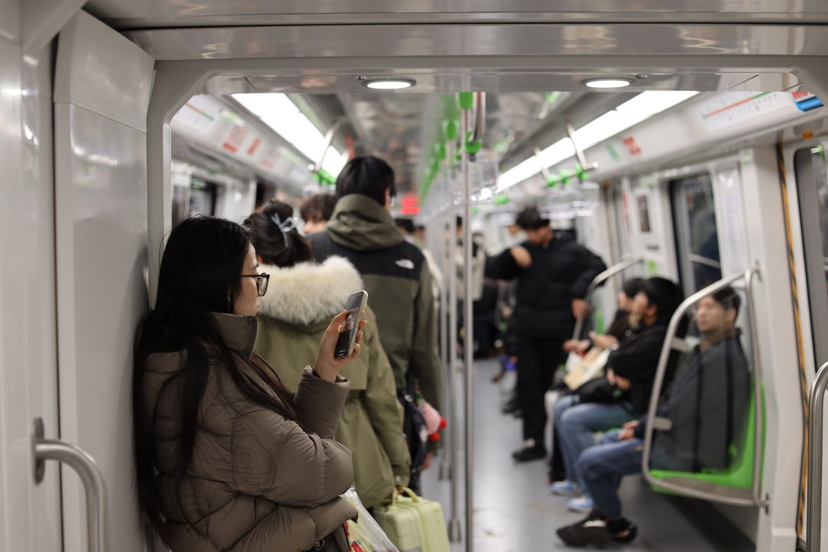 Pasajeros usando sus teléfonos a bordo de un tren de metro en Nankín, China