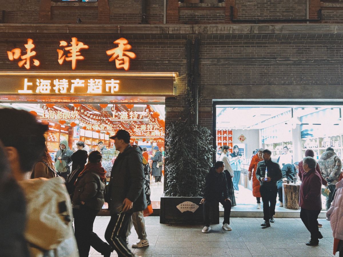 Concurrida calle comercial de Shanghái de noche con grandes carteles de tiendas en caracteres chinos iluminados sobre los peatones