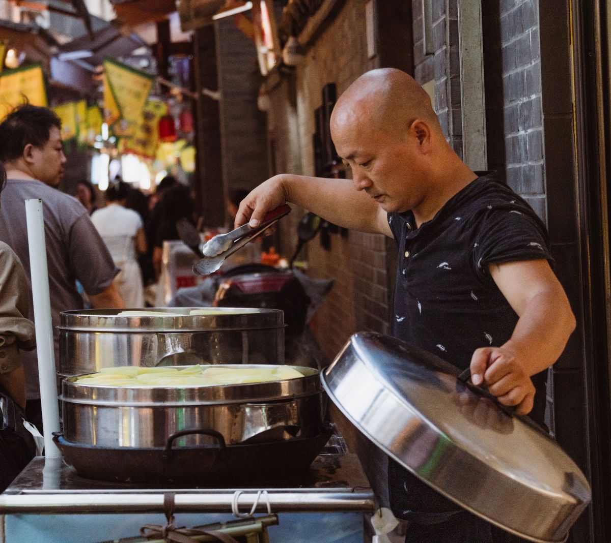 Un vendedor de comida callejera cocinando al vapor en un mercado concurrido