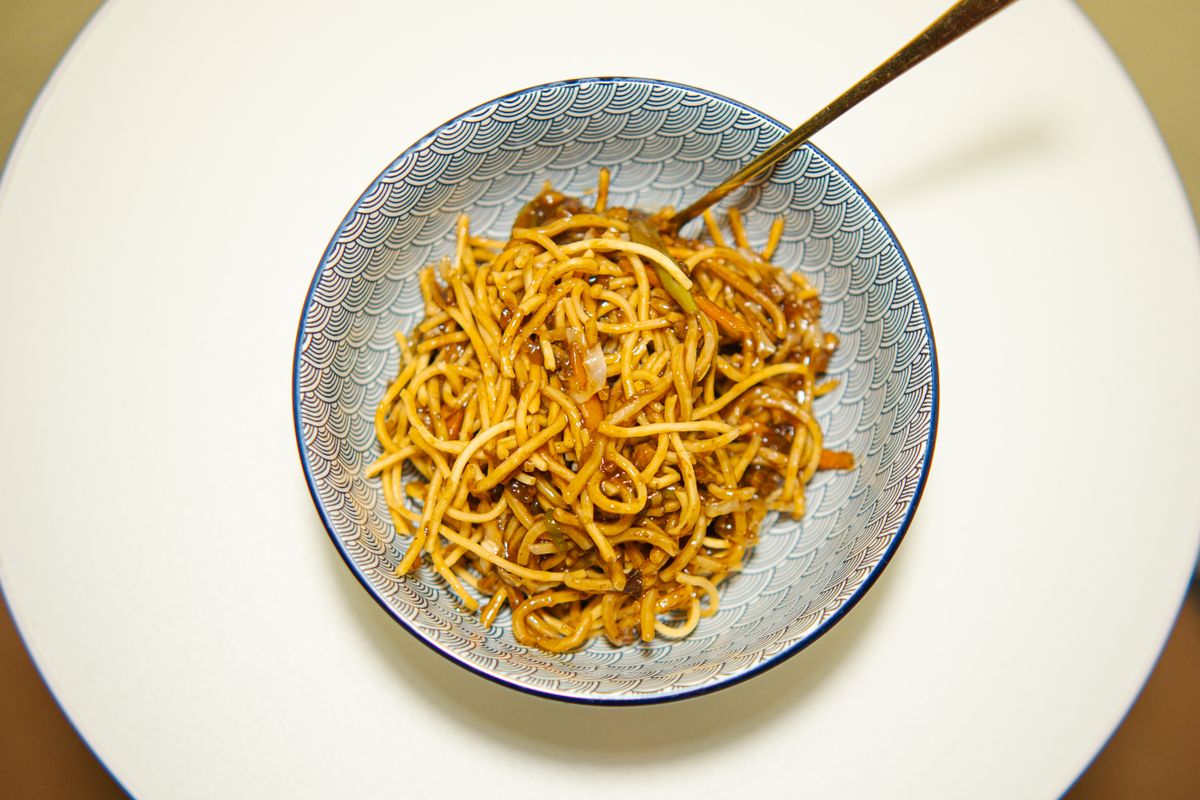Un tazón de fideos fritos chinos con palillos
