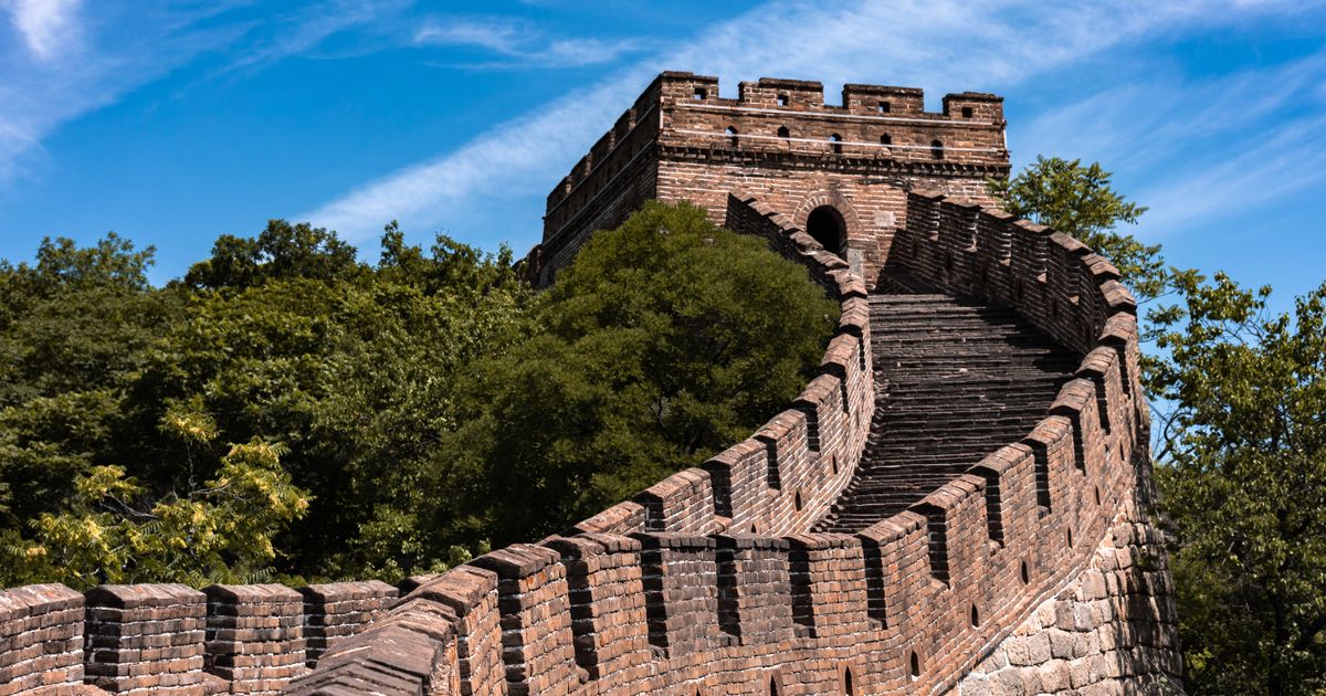 Torre de piedra y almenas de la Gran Muralla de Mutianyu bajo un cielo azul