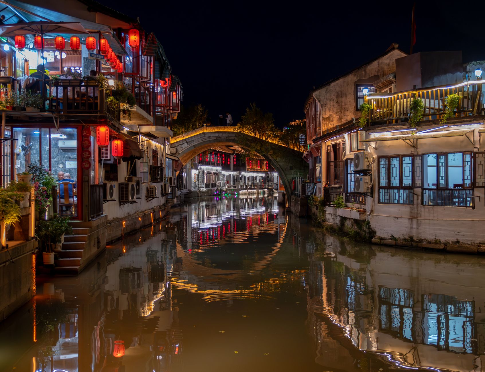 Puente arqueado y farolillos rojos sobre el canal