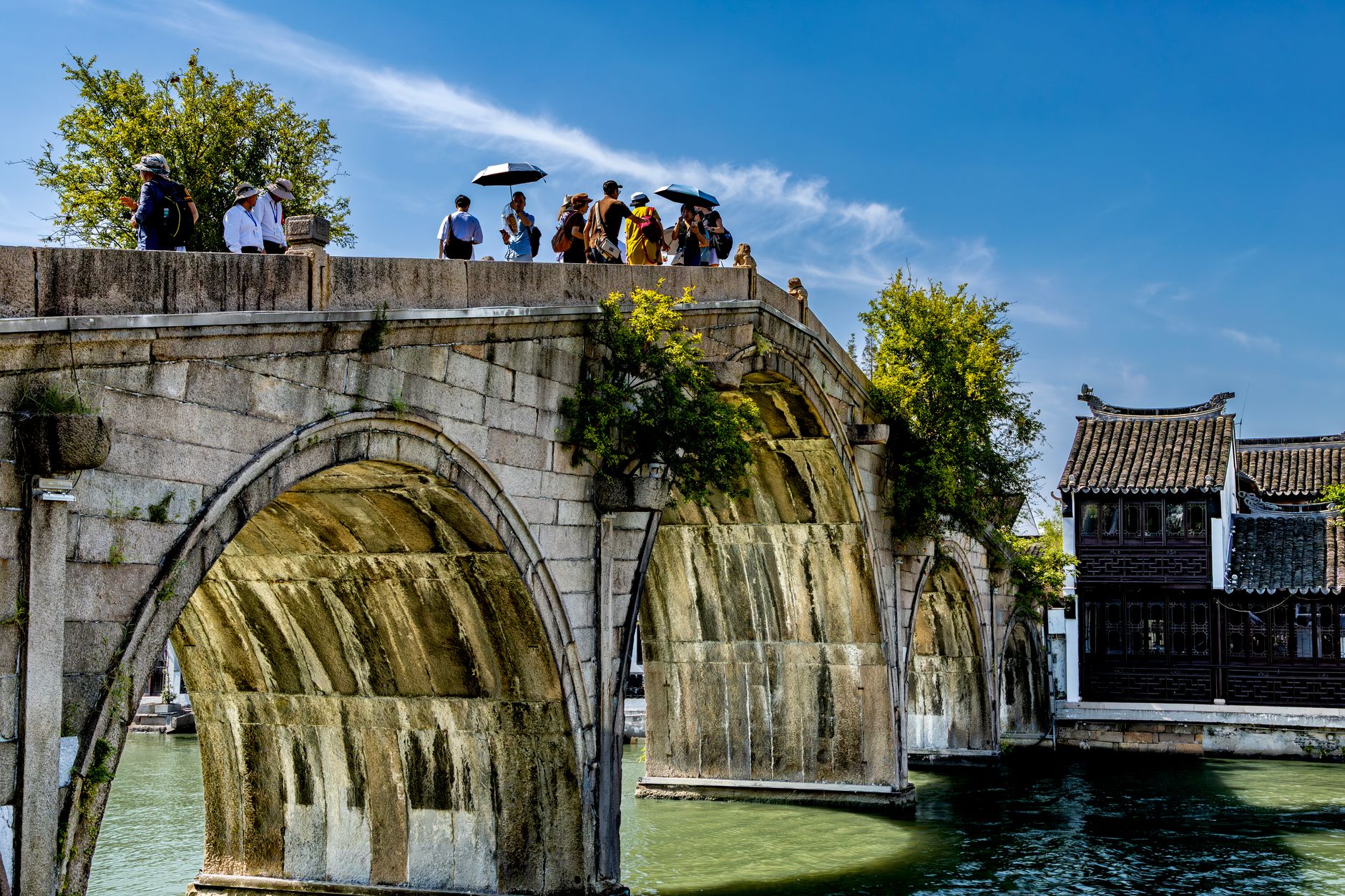 Tourists on the arched stone bridge over the canal