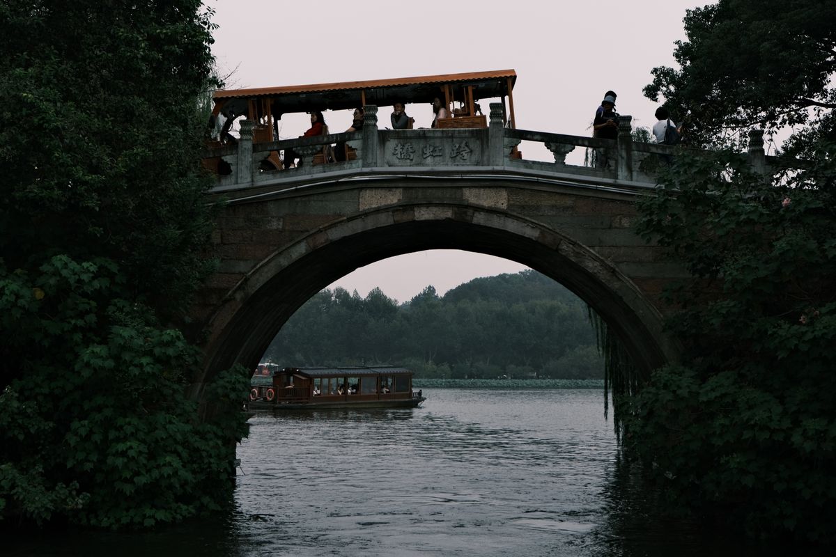 El Gran Canal en Hangzhou con casas tradicionales, un puente de arco de piedra y torres modernas