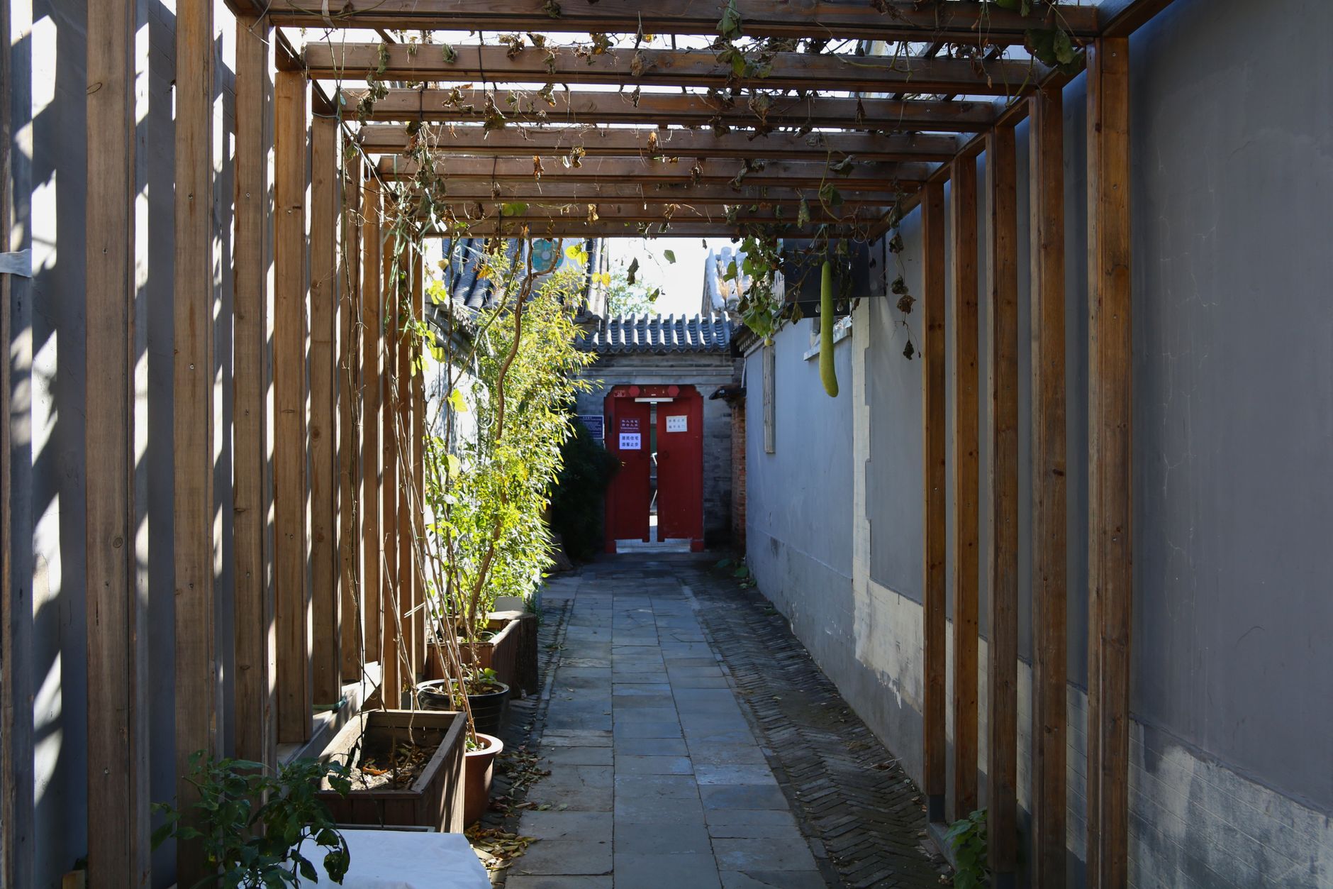 La entrada de un sereno patio hutong con una puerta roja tradicional