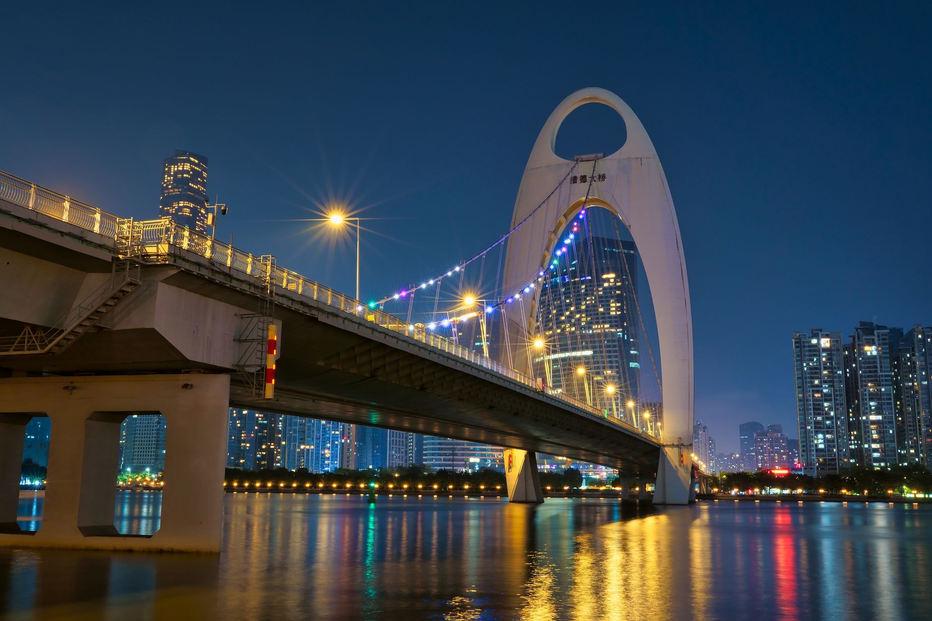 El puente Liede sobre el río de las Perlas, iluminado en color ante el horizonte nocturno de Cantón
