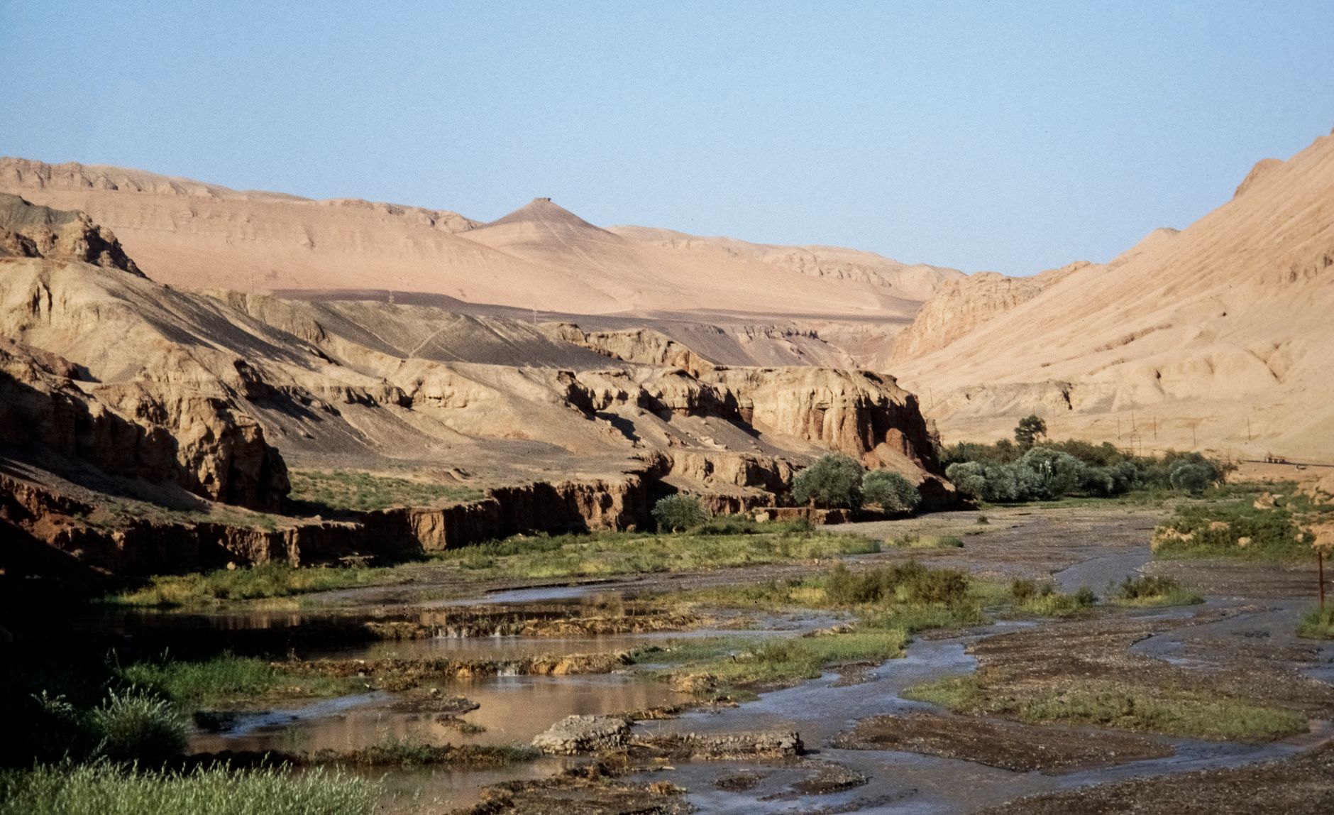 Acantilados áridos y un fino arroyo del desierto en el valle del río Dang, bajo el Monte Sanwei