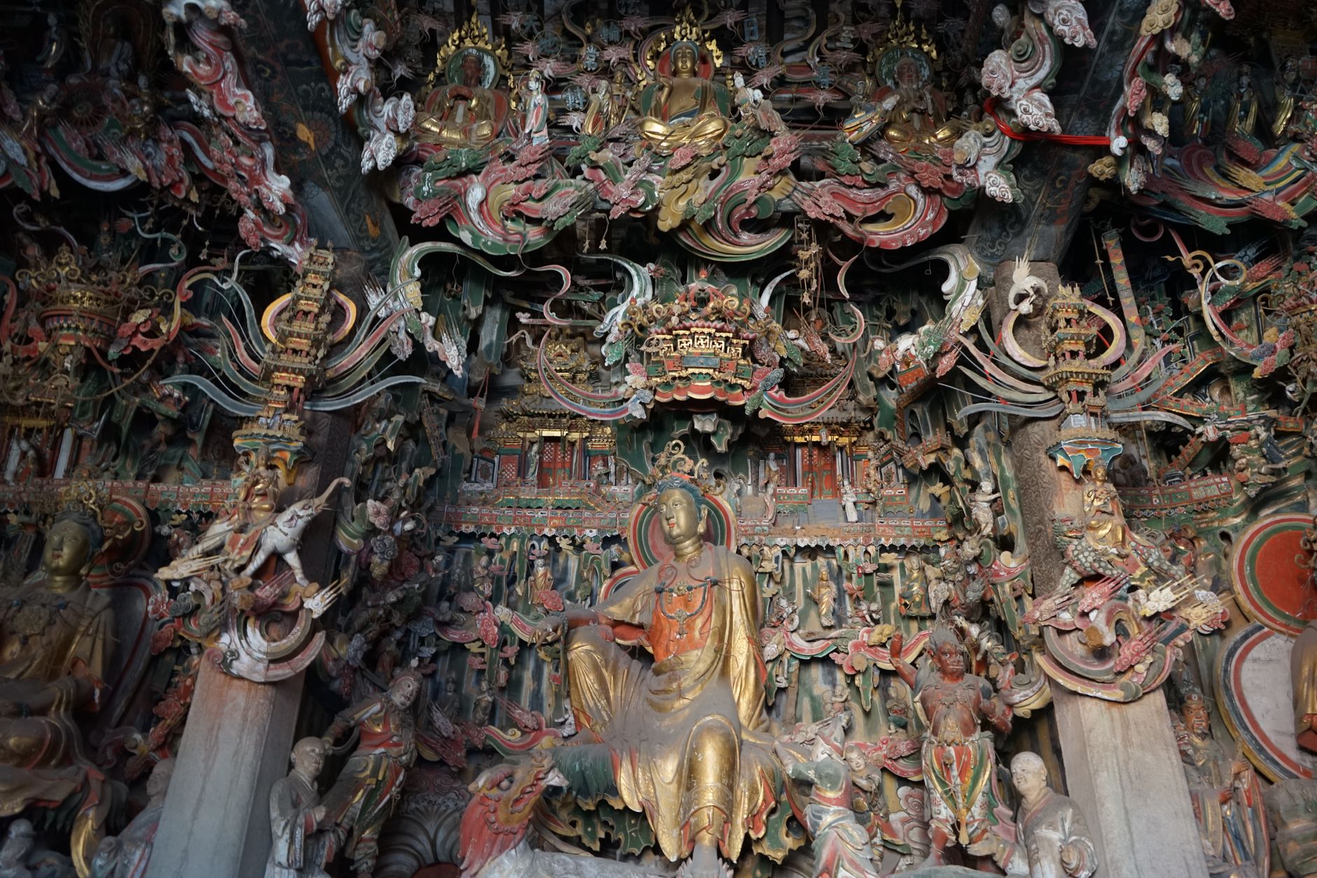 Estatuas budistas doradas y tallas intrincadas dentro de un salón-templo de montaña