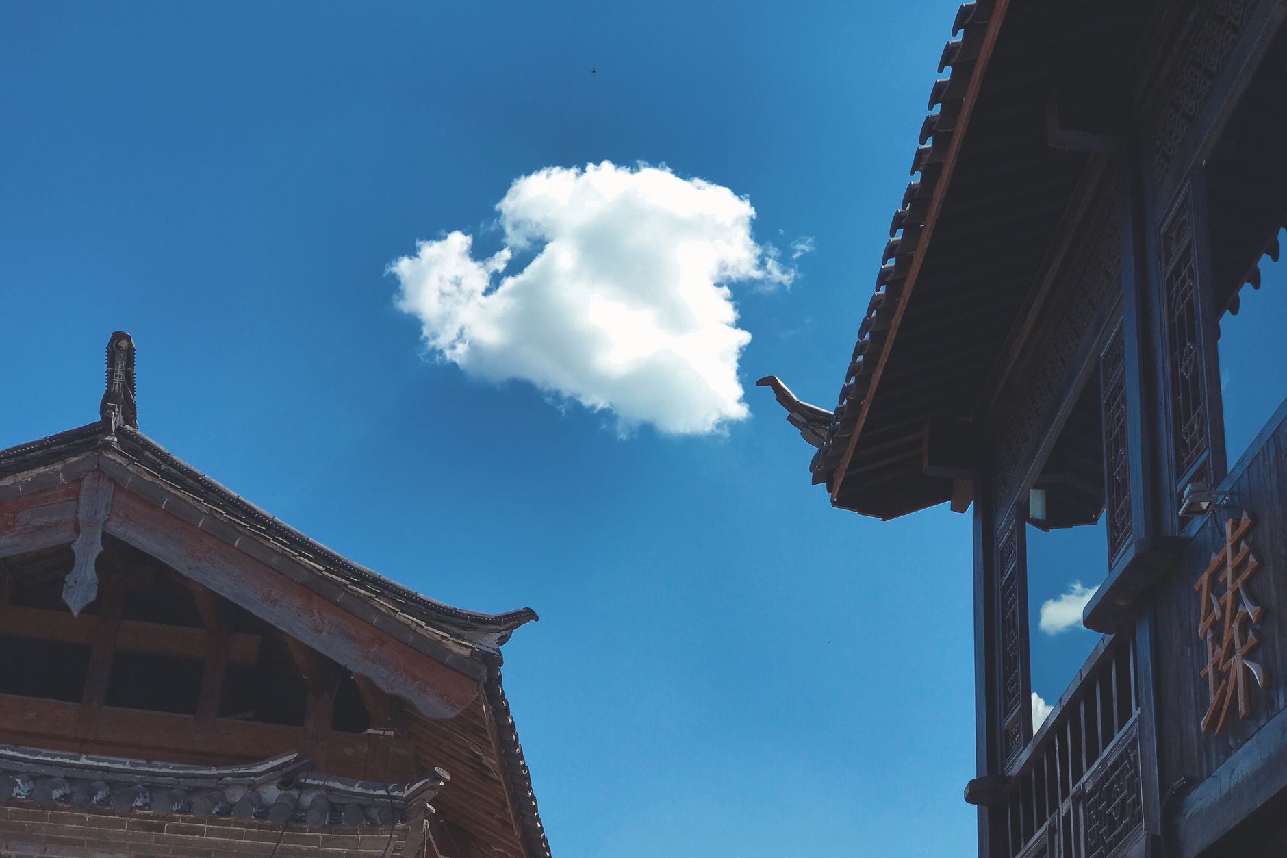 Tejados de madera naxi bajo un cielo azul intenso en el Casco Antiguo de Lijiang