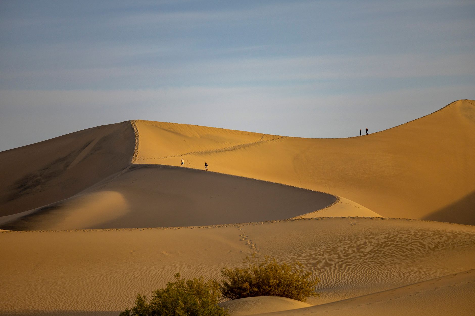 Visitantes subiendo las dunas cantarinas al atardecer