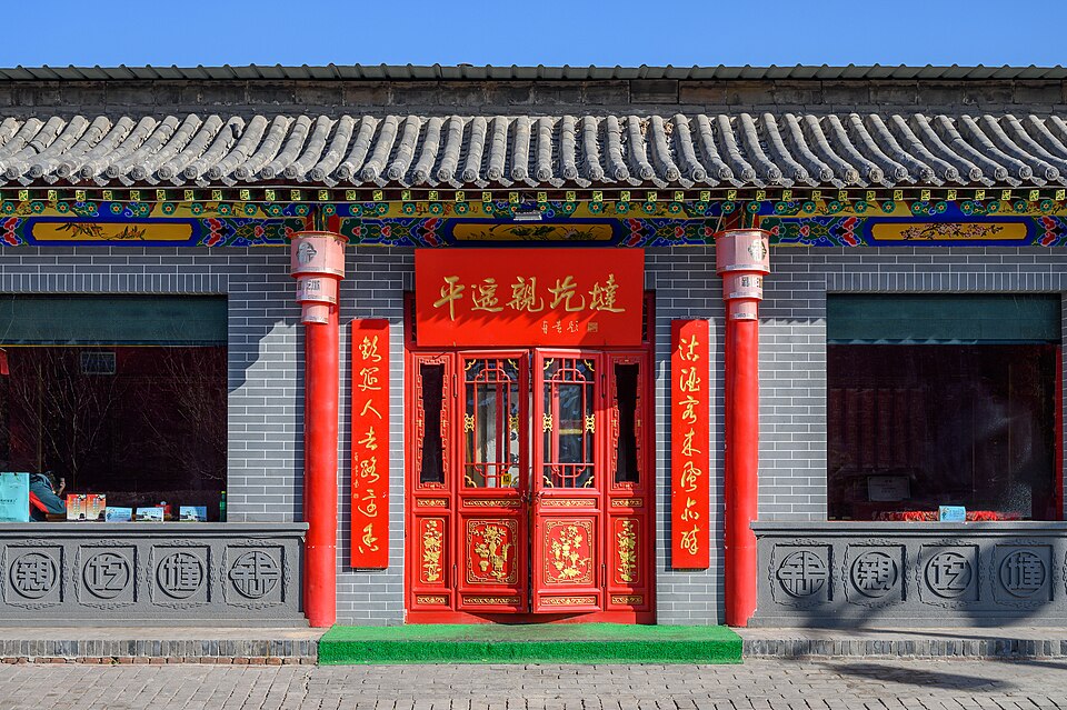 Una fachada Qing restaurada de ladrillo gris con puertas rojas e inscripciones en la Calle Ming-Qing