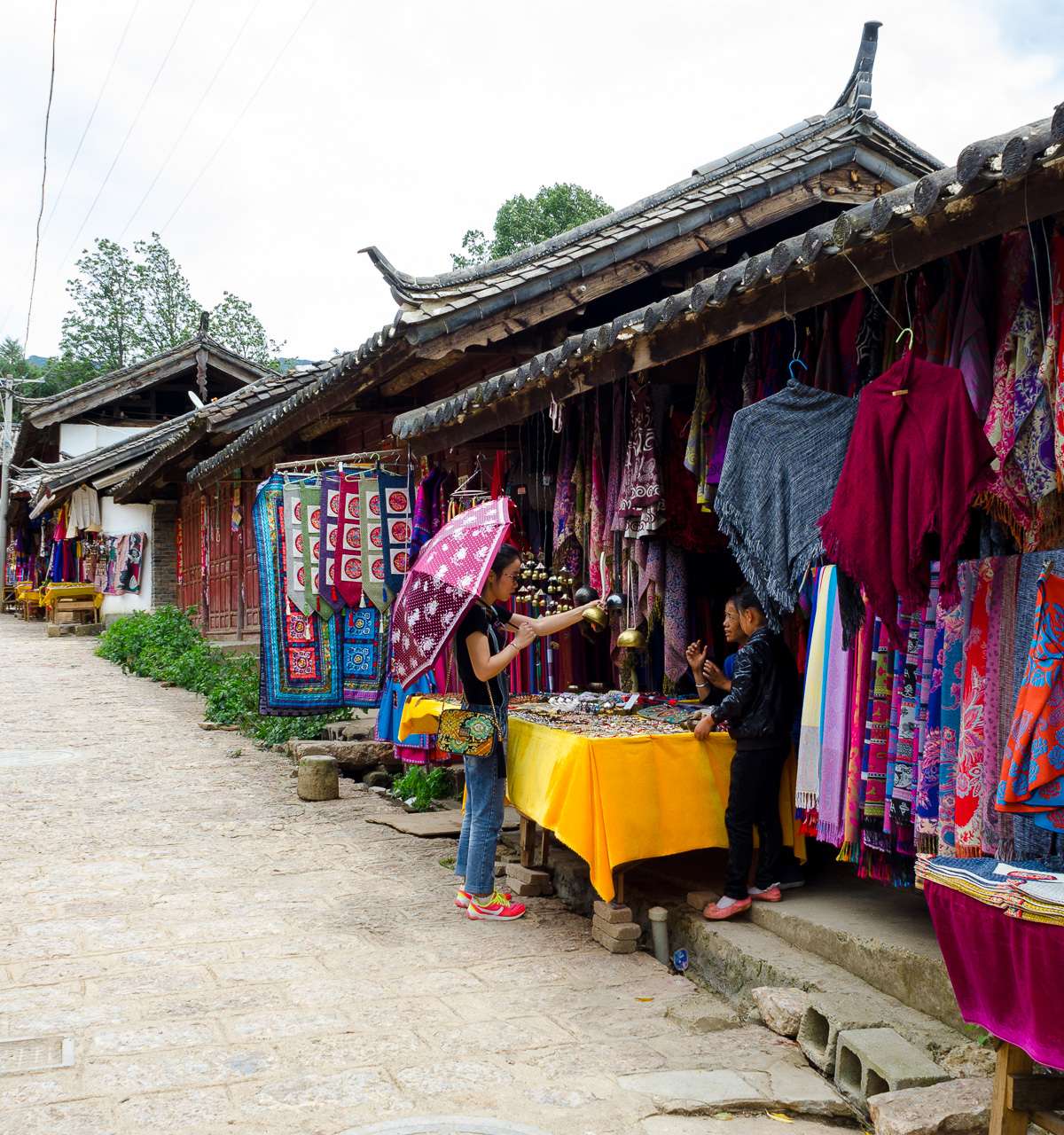 Calle principal del pueblo antiguo de Baisha con un puesto de artesanía naxi