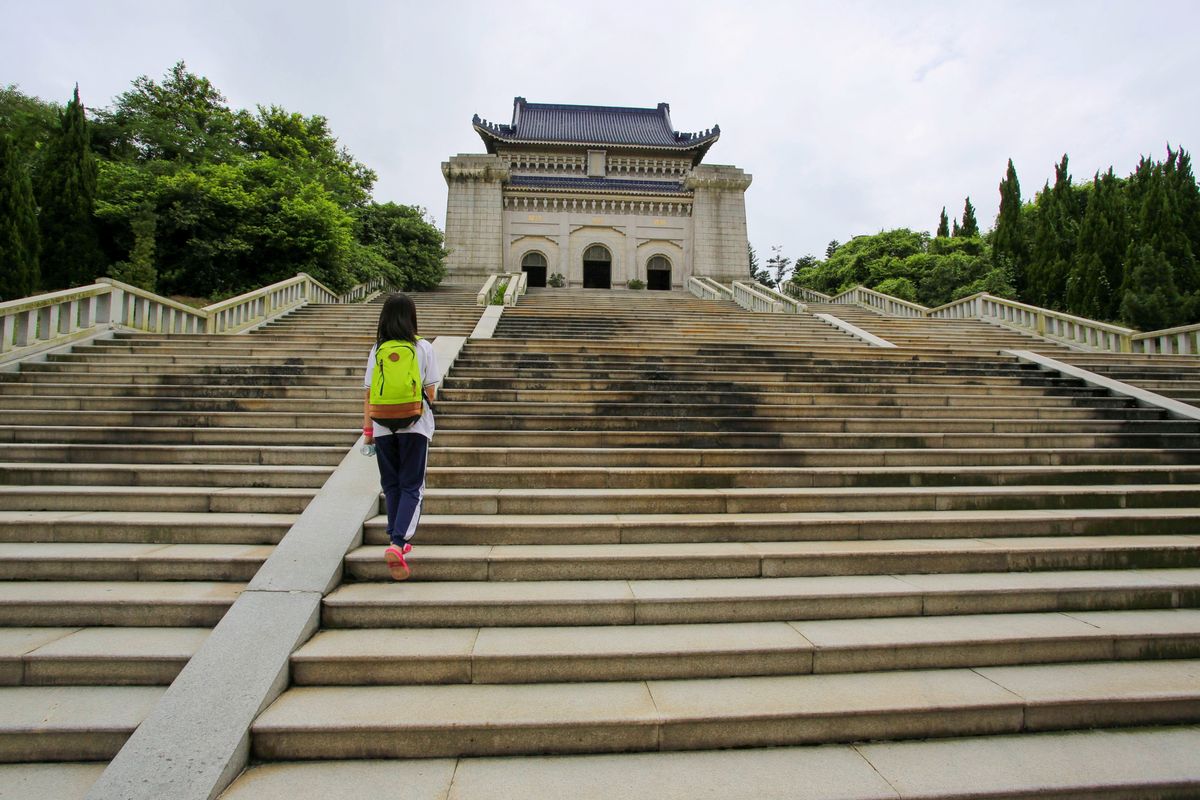 A visitor on the mausoleum steps with forest behind