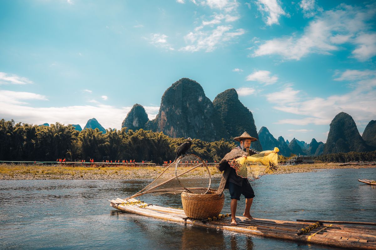 Turistas en una balsa de bambú impulsada por el verde río Yulong