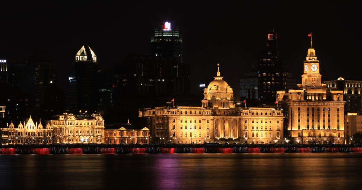 The Bund waterfront in Shanghai lit up at night with the Huangpu River in the foreground