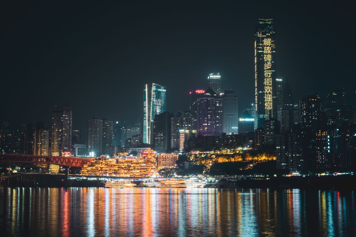 Chongqing skyline and Hongyadong reflected in the river at night, with the Jiefangbei pedestrian street neon sign visible