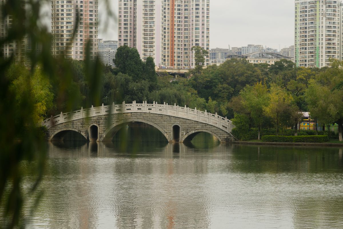 Stone arch bridge over a lake in Kunming, Yunnan, framed by willow trees