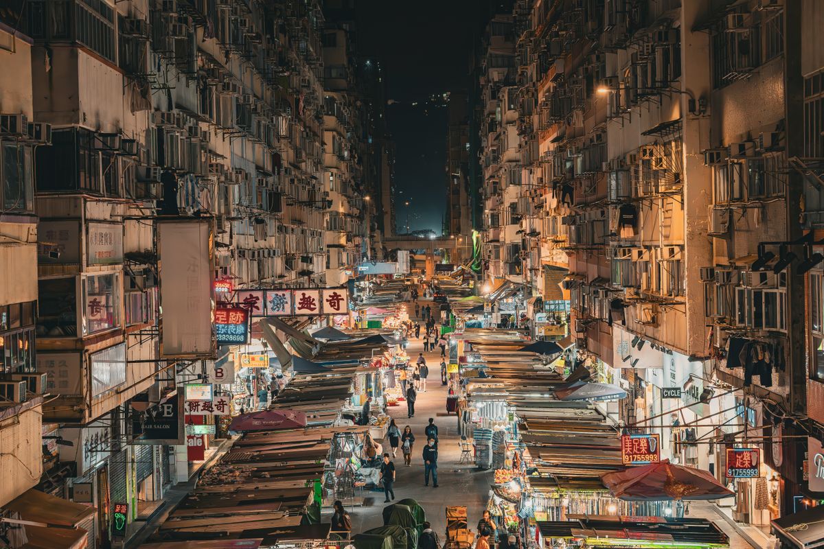 Illuminated Mong Kok market street at night with stalls and neon signs
