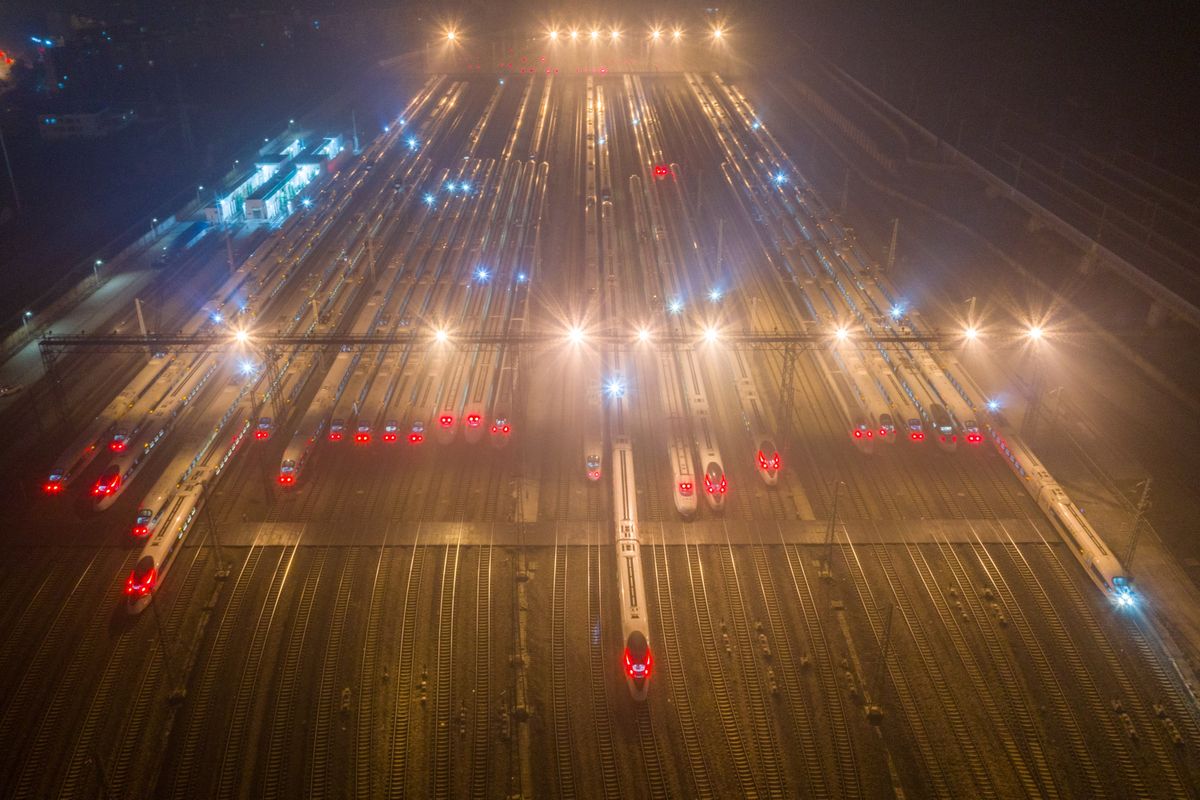 Aerial view of high-speed trains lined up at an illuminated railway station in Nanjing at night