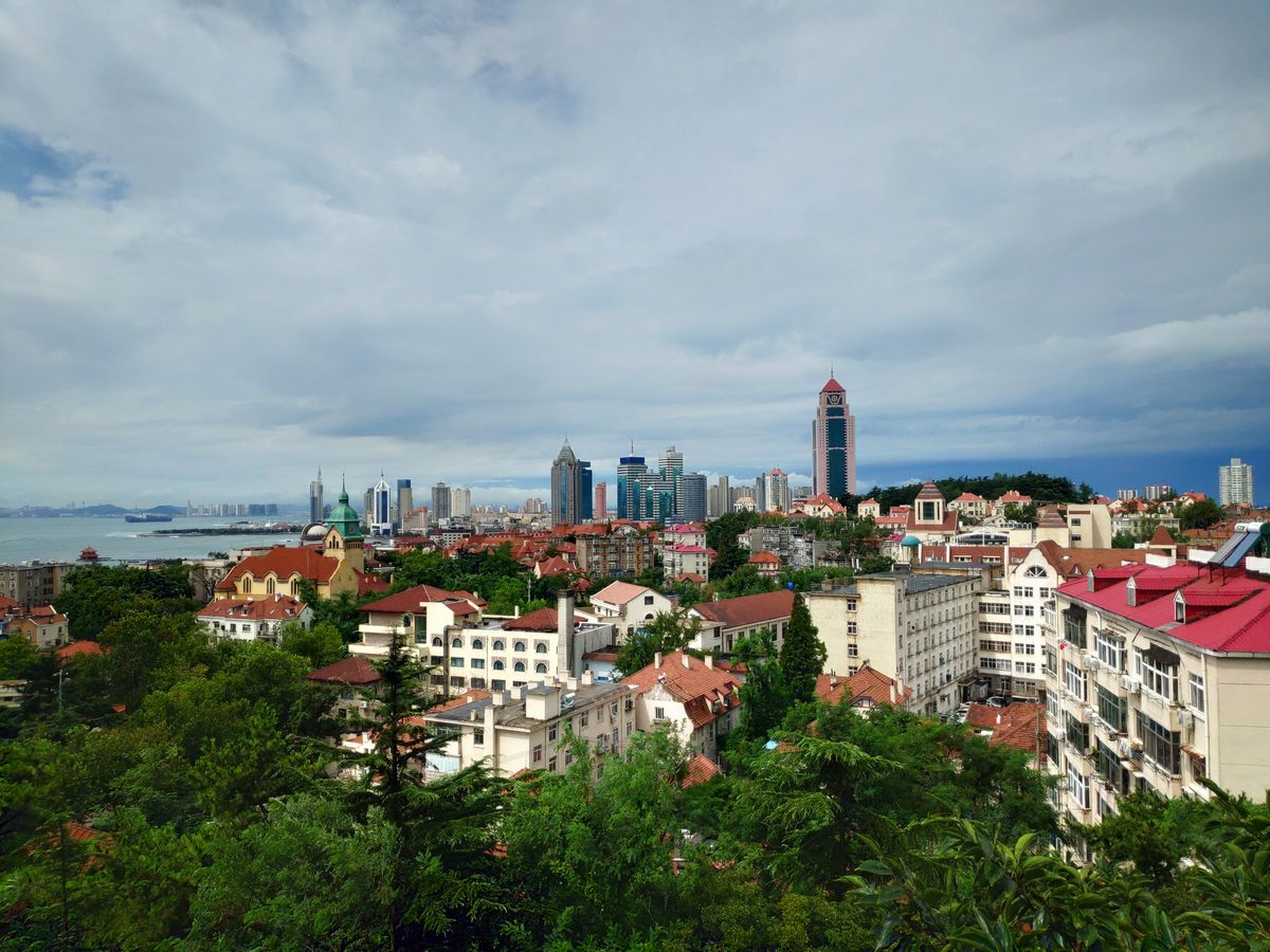 Red-tile roofs of Qingdao's German-era old town with the modern skyline behind