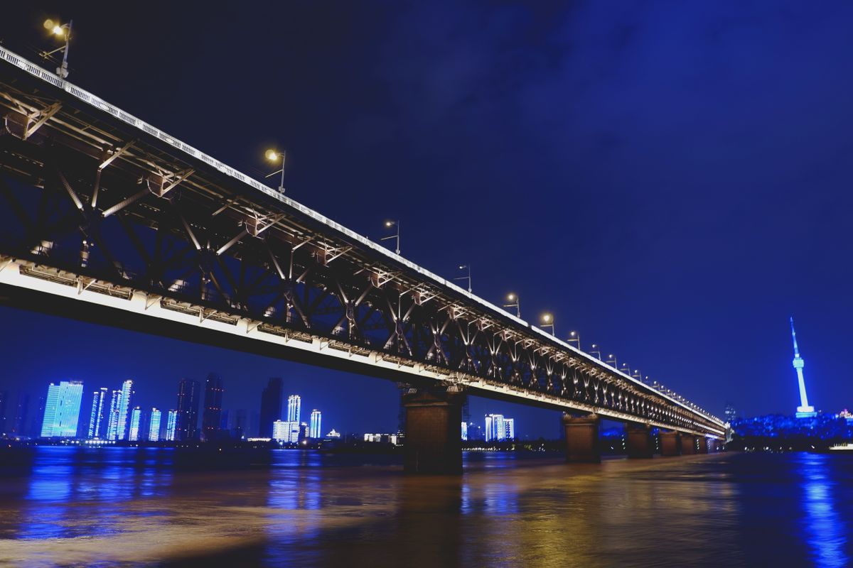 Wuhan's Yangtze River Bridge lit up at night, seen from the Hankou riverside