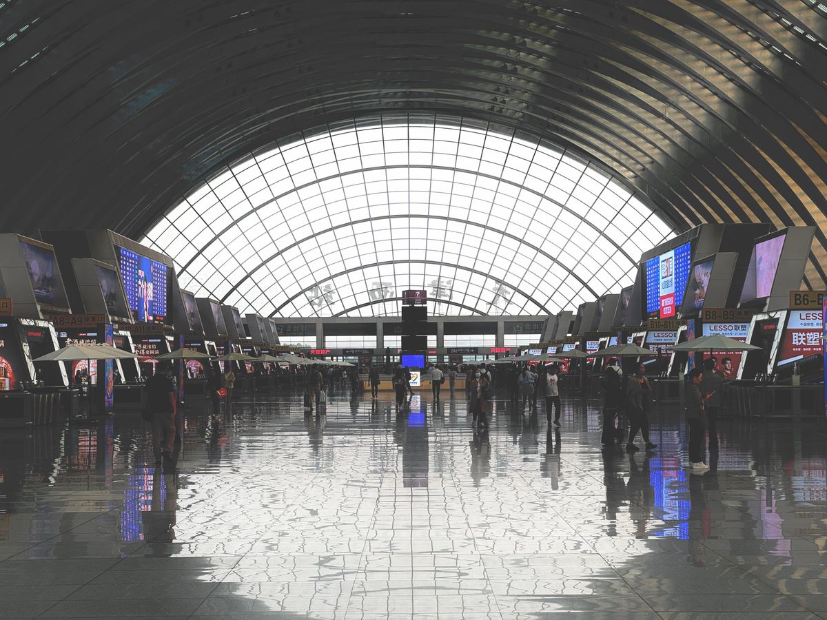 Modern high-speed rail station interior with glass roof, similar to Tianjin's train stations