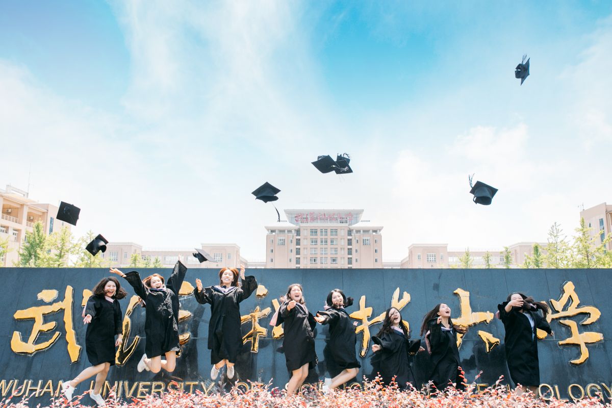 Graduates celebrating outside a university campus gate in Wuhan's Guanggu district