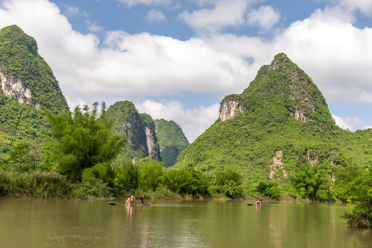 Bamboo rafts carrying visitors past karst peaks on a river near Yangshuo