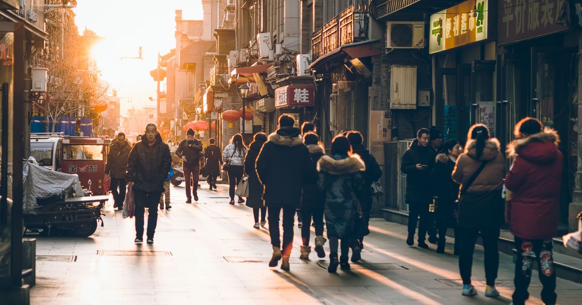 Pedestrians walking a sunlit street in Beijing at sunset