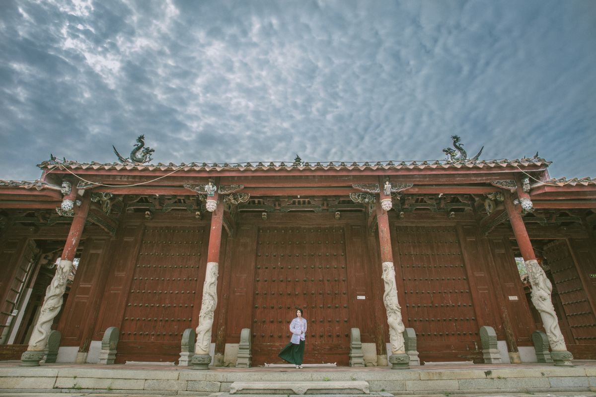 A solo traveler standing in the courtyard of a traditional temple gate in China