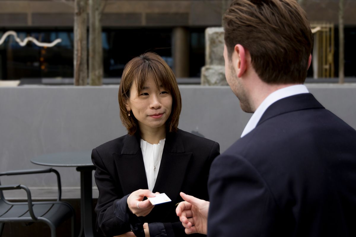 Business professional handing over a card with both hands during an outdoor meeting