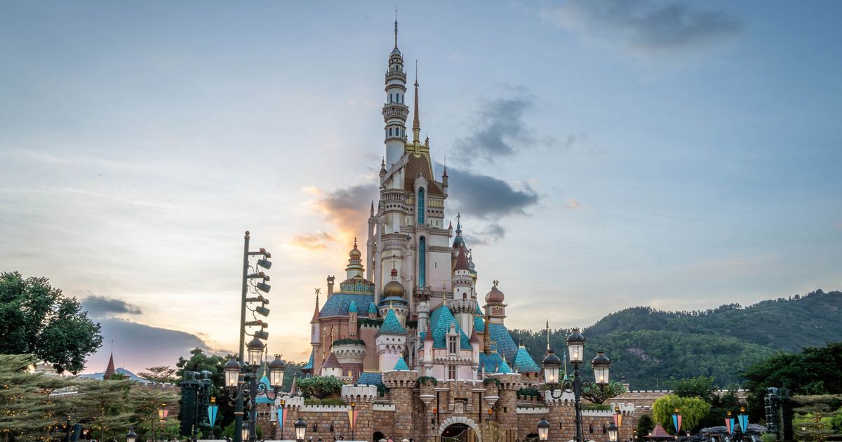 Hong Kong Disneyland castle at dusk with visitors gathered in front