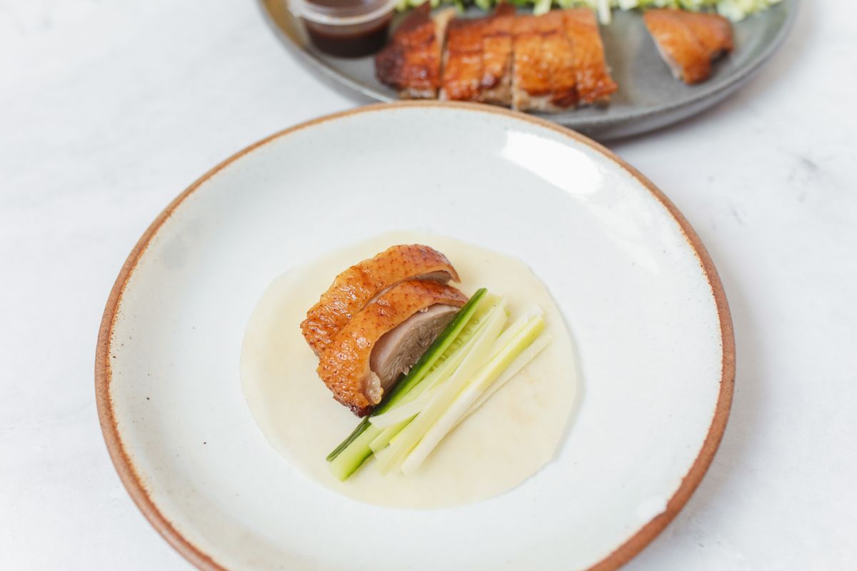 Sliced roast duck served with cucumber batons on a plate, in the imperial northern Chinese banquet style