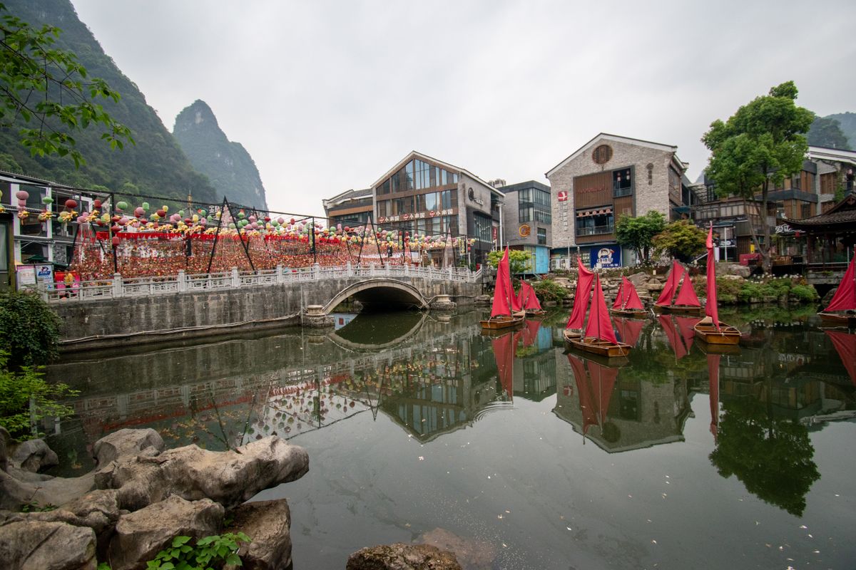 Colorful tour boats on the water in Yangshuo with karst peaks behind the old town