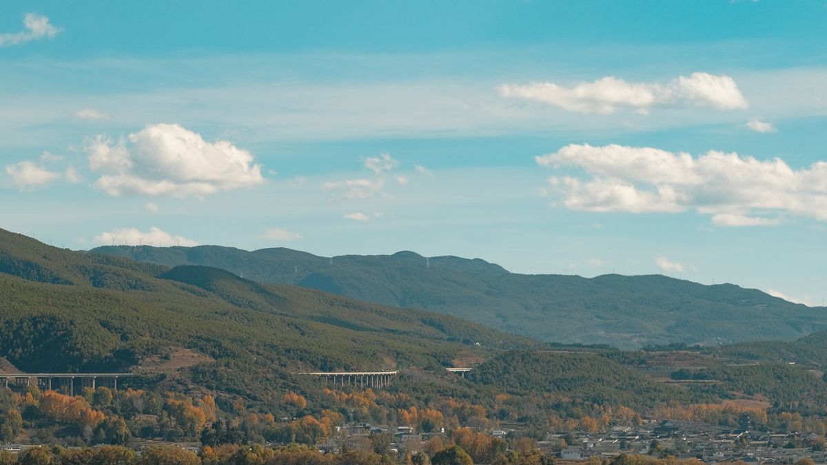 Autumn view of hills and a highway viaduct near Dali, Yunnan, illustrating the distance between the railway station and the old town