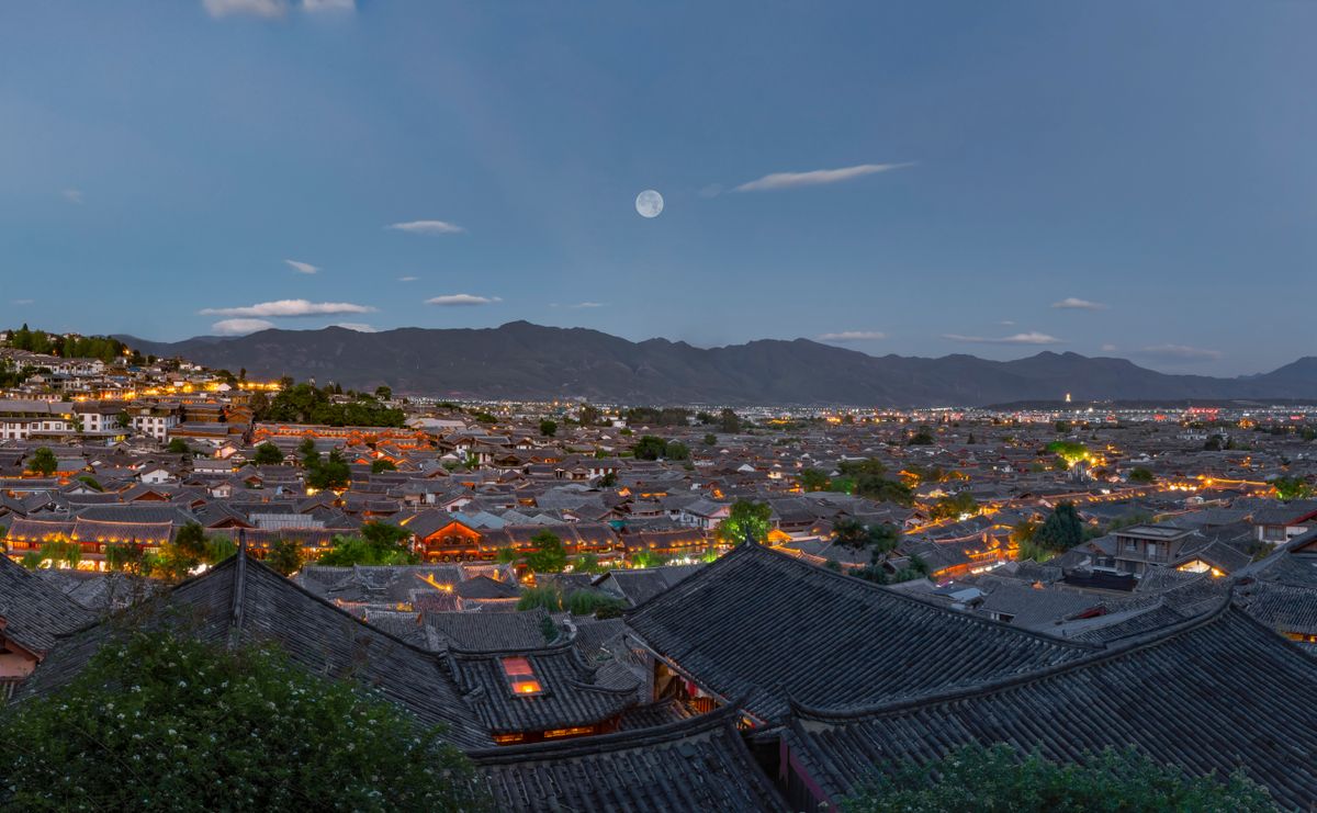 Lijiang Old Town at dusk with the moon rising over the rooftops