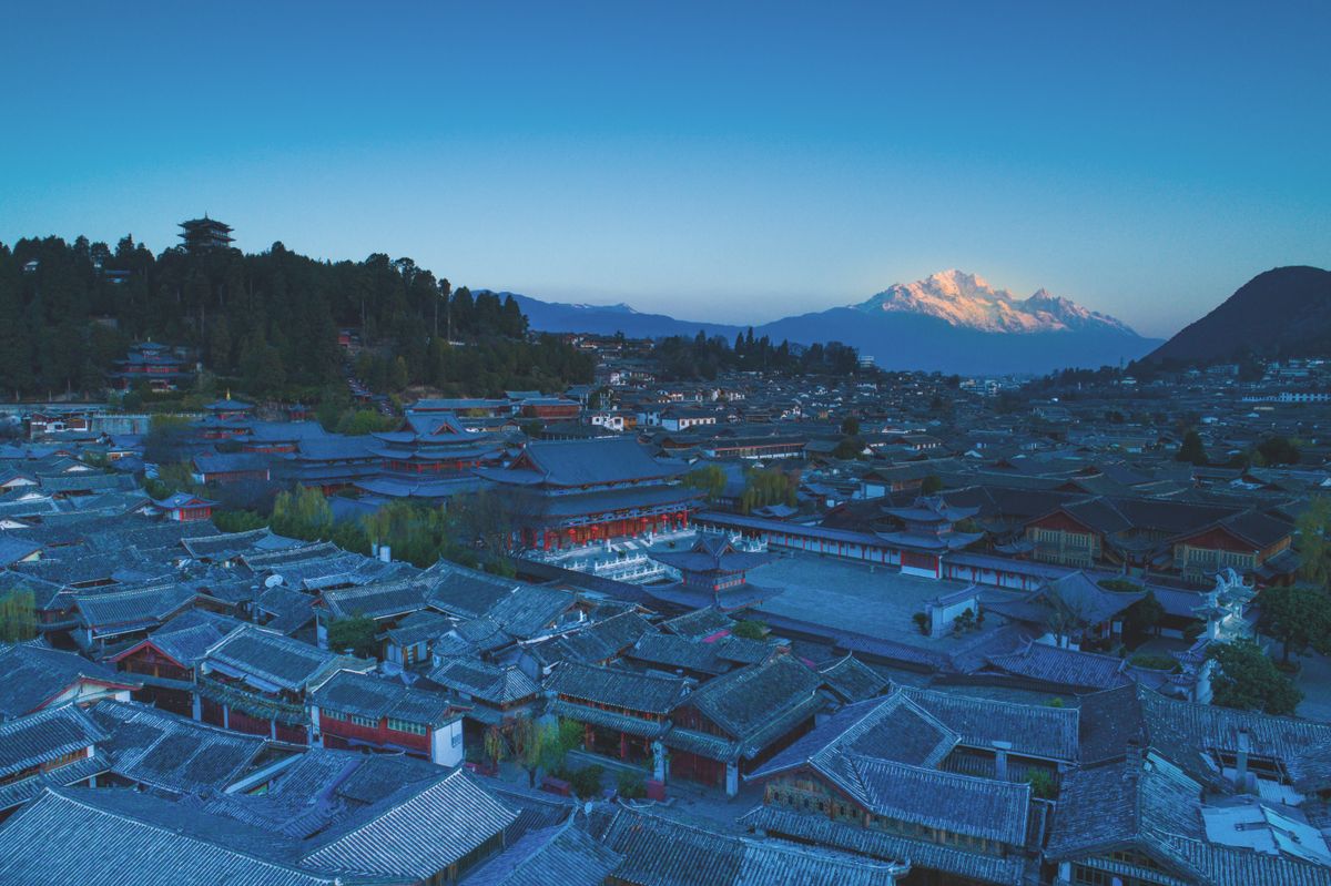 Aerial dusk view of Lijiang Old Town with Jade Dragon Snow Mountain in the background