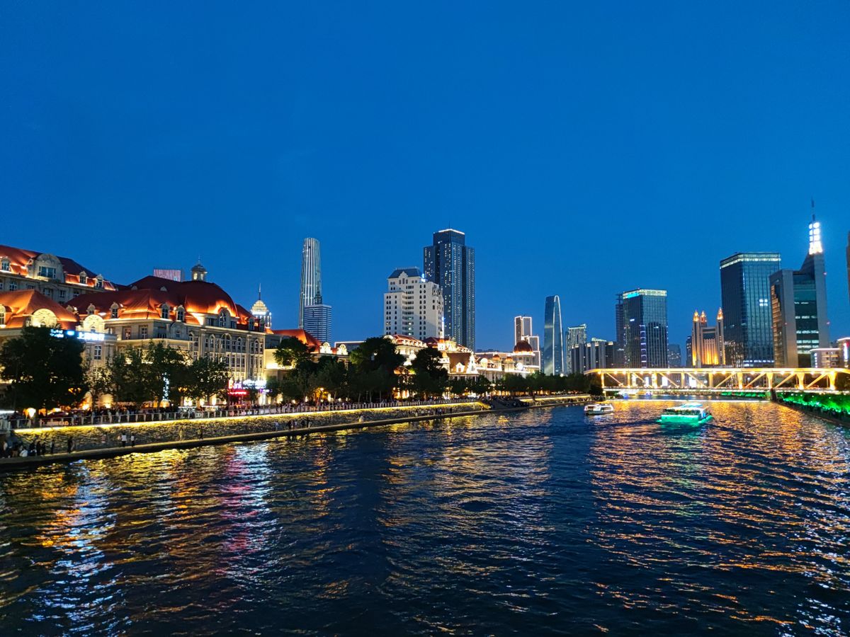 Horizonte de Tianjin y barcos de crucero por el río iluminados de noche