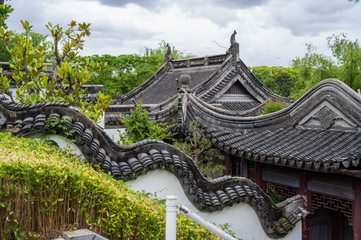 Classical Suzhou garden with an undulating white wall and dark tile roofline