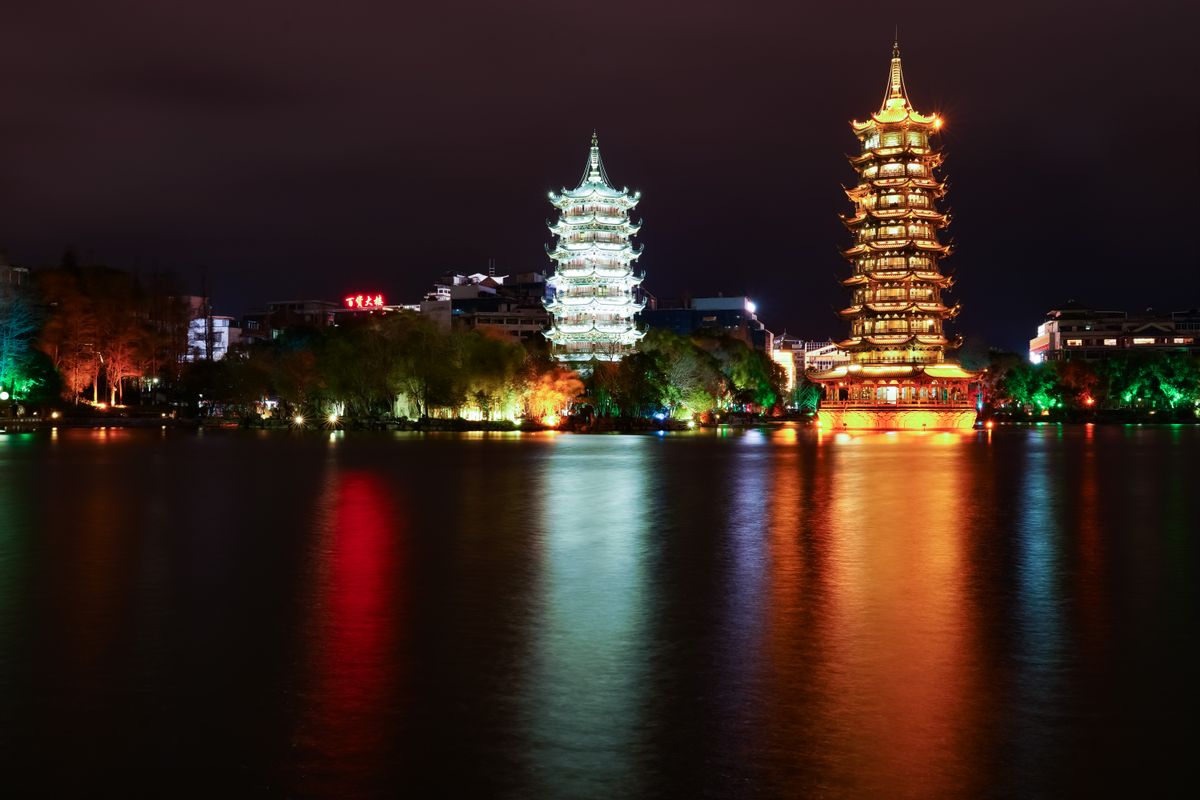 Sun and Moon Pagodas illuminated at night on Shan Lake in Guilin