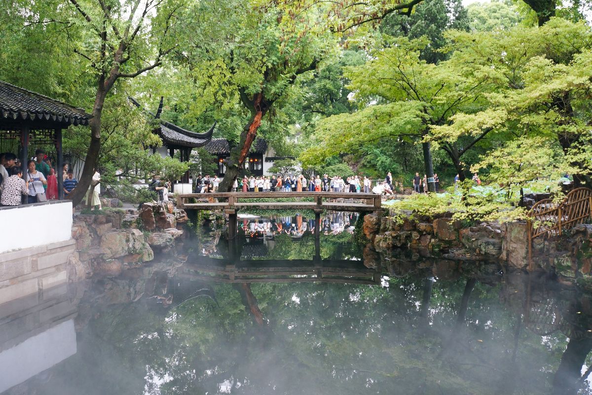 Pabellón de un jardín clásico de Suzhou y puente de piedra reflejados en un estanque